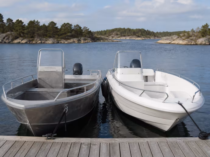En aluminiumbåt och en glasfiberbåt ligger sida vid sida vid en brygga.