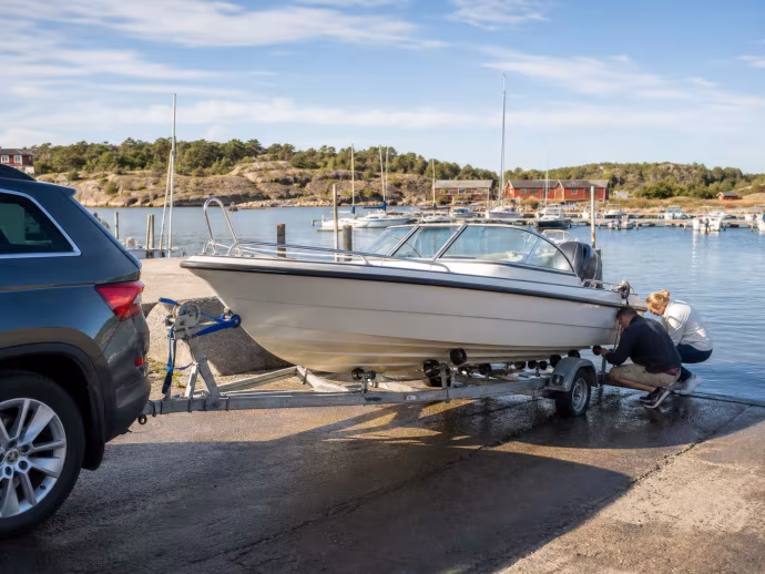Motorbåt på trailer förbereds vid en sjösättningsramp.