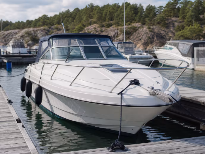 Motorbåt ligger förtöjd med linor och fendrar i en marina.