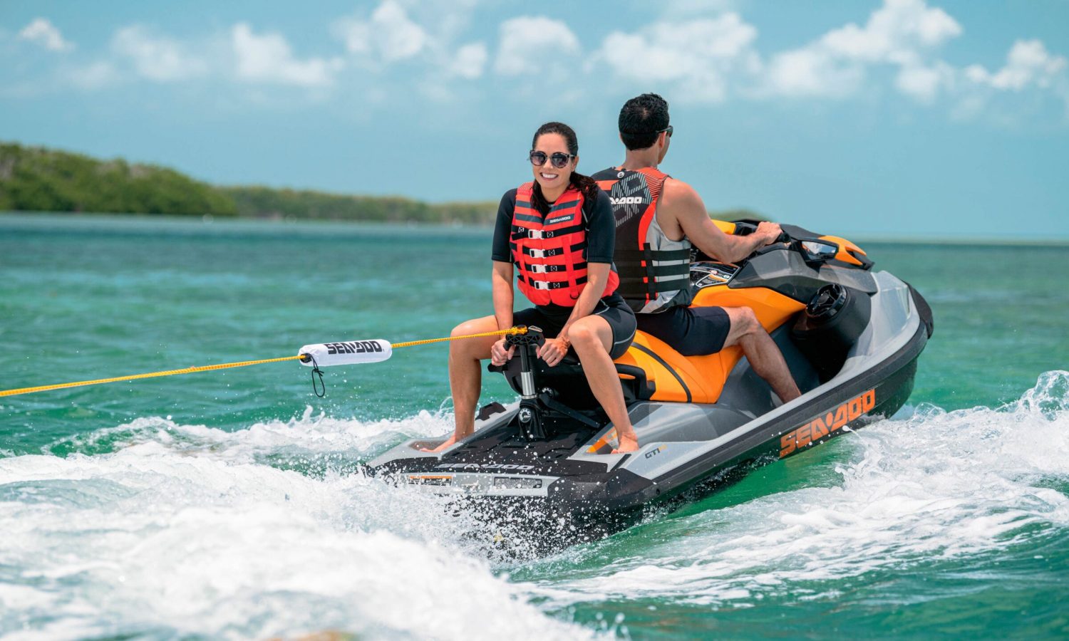 A couple riding on a Sea-Doo GTI SE and pulling their kid behind